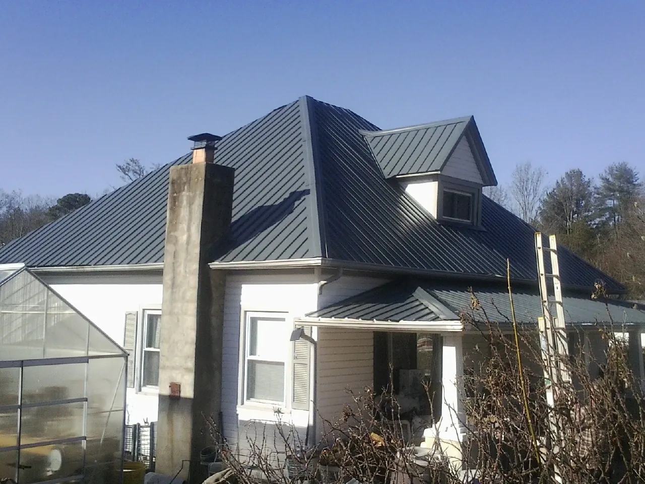 Dark blue standing seam metal roof on a white farmhouse with dormer — Slate & Tile Roof Repair by Roofing Brothers in Perry Hall