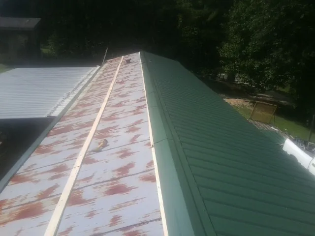 Old rusted panels beside newly installed green metal roofing — Wind Damage Roof Repair by Roofing Brothers in Perry Hall