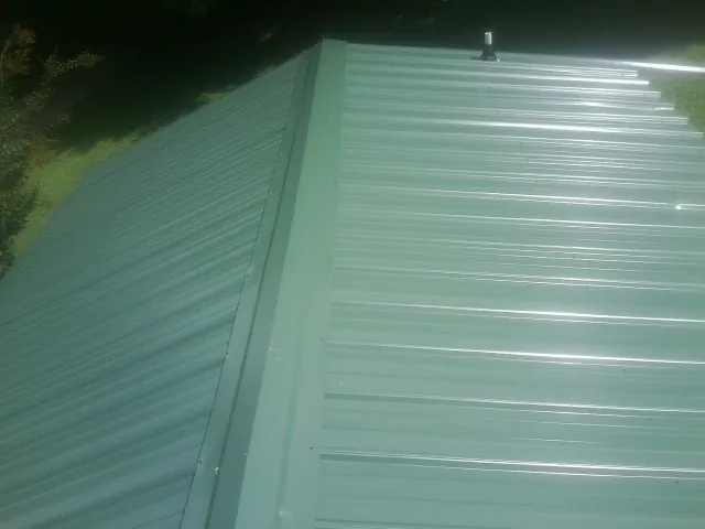 New green metal panels meeting at the ridge of a roof — Flat Roof Repair work by our crew in Perry Hall