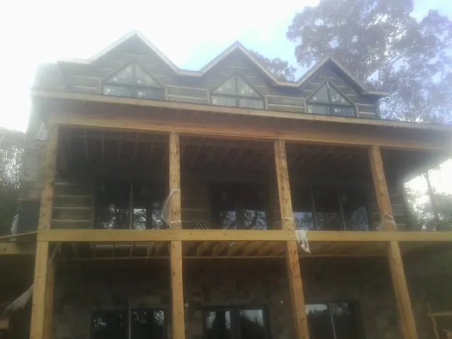 Dormers and porch framing on a large log home under construction — Roof Coating work by our crew in Perry Hall