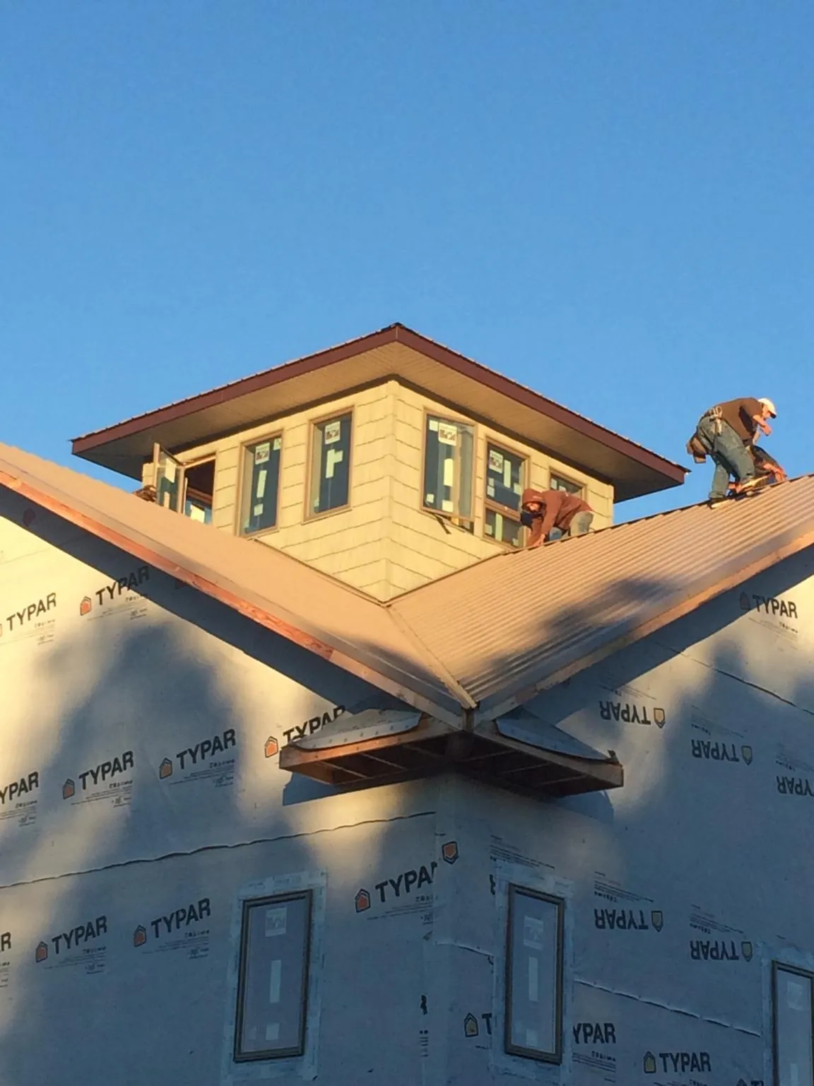 Roofers working around a rooftop cupola on a new metal roof at sunset — Roof Waterproofing in Perry Hall by Roofing Brothers